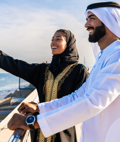 Traditional arab couple wearing emirati clothing dating outdoors - Middle-eastern married woman with abaya and man with kandura meeting and having fun in the city