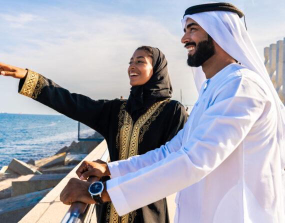 Traditional arab couple wearing emirati clothing dating outdoors - Middle-eastern married woman with abaya and man with kandura meeting and having fun in the city